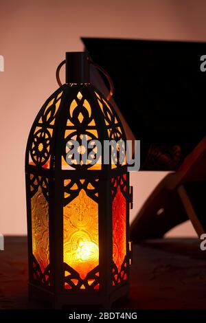 Ornamental Arabic lantern with burning candle glowing in dark and Holy Quran. Festive greeting card, invitation for Muslim holy month Ramadan Kareem Stock Photo