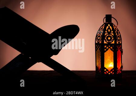 Ornamental Arabic lantern with burning candle glowing in dark and Holy Quran. Festive greeting card, invitation for Muslim holy month Ramadan Kareem Stock Photo