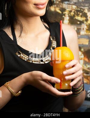 woman holding a glass of orange juice garnished with halved orange Stock Photo