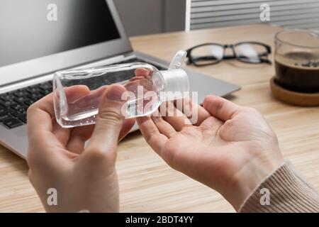 Closeup womans hand uses antibacterial gel to prevent coronavirus on her workplace. Hand sanitizer alcohol gel is pouring from a bottle on a Stock Photo