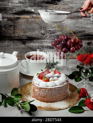 woman sieve sugar powder on fruit cake Stock Photo