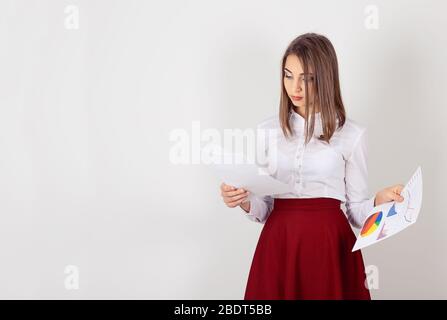 Attractive young businesswoman working on documents, analyzing company annual report. One single person isolated white wall background. Copy space. Stock Photo