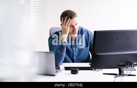 Stressed Young Businessman Sitting At Desk In Office Stock Photo