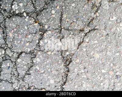 The surface of the gray asphalt with a cracks. Texture of old rough asphalt. Stock Photo