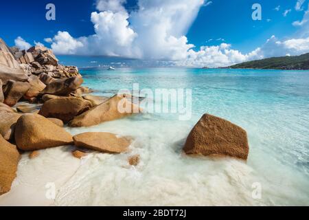 Stones on tropical sandy beach with crystal clear blue ocean bay at La Digue Island, Seychelles. Stock Photo