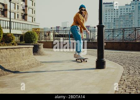 Skateboarding at city. Female, enjoyment. Hipster girl riding skate board. Ride, style. Extreme sport and emotions concept. Alternative lifestyle Stock Photo