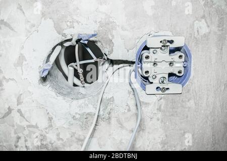 Close-up of holes for installing an electrical outlet and exposed electrical wires for a wall outlet. Repair of electrical wiring in the house. Stock Photo