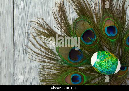 One Easter creativity decorated eggs with peacock feathers on a wooden background Stock Photo