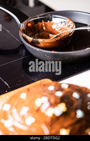 Hot chocolate melted on a black pan with chocolate cake in the foreground Stock Photo