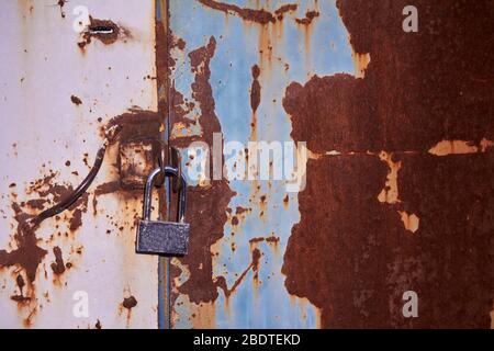 Multicolored background, rusty metal surface with blue paint flaking and metal door with padlock Stock Photo