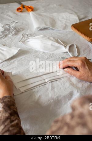Woman make a protective mask at home. View of person sewing medical mask because the lack of stock in stores during quarantine for coronavirus. Stock Photo