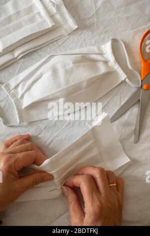 Woman make a protective mask at home against covid 19. Top view of person sewing and materials to make a medical mask. DIY mask. Stock Photo