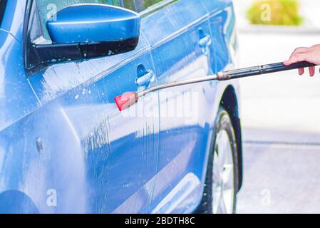 Man Washing His Car With A High Pressure Hose With A Fine Mist