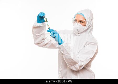 Female doctor in a protective white suit with a syringe in his hands and blue rubber gloves stands in different poses Stock Photo