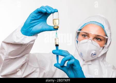Doctor, nurse or scientist hand in blue nitrile gloves holding flu, measles, coronavirus COVID-19 vaccine. Stock Photo
