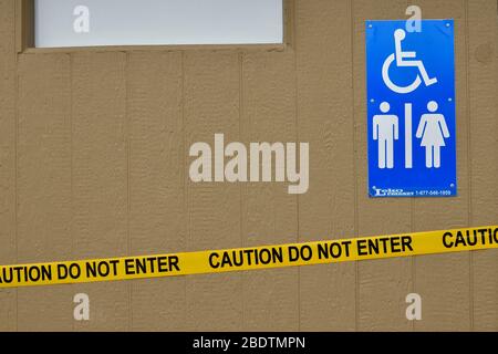 A close up of the caution tape on an outdoor toilet at a park in rural Alberta Canada. Stock Photo