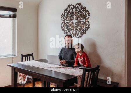 Wide view of father trying to work from home with toddler standing Stock Photo