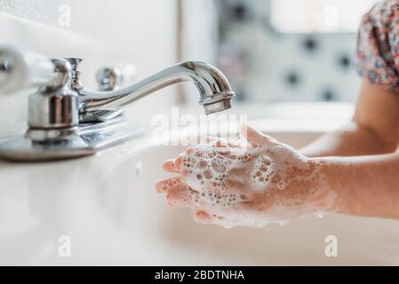 Close up view of young child washing hands with soap in sink Stock Photo