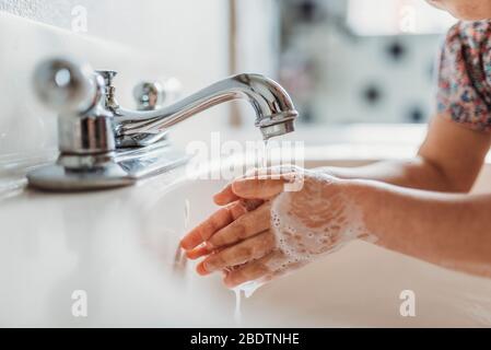 Close up view of young child washing hands with soap in sink Stock Photo