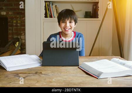 Small male student is happy while being home schooled during quarantine - Books and Studies - Concept Study at Home Stock Photo