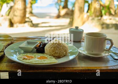Breakfast on Boracay island of the Philippines with views of the white sandy beach and sea. An omelet and a Cup of coffee in a white dish Stock Photo