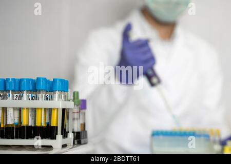 Lab technician analyzes blood test in laboratory. Focus on blood samples in rack Stock Photo