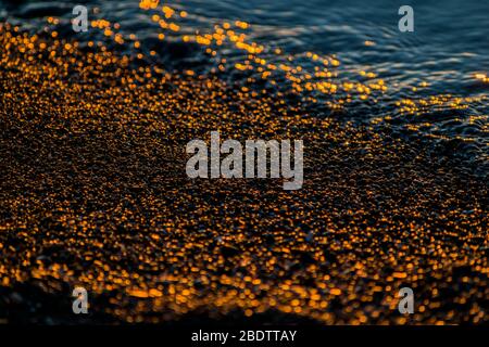 Pebbles at sunrise, stones and water on the beach Stock Photo