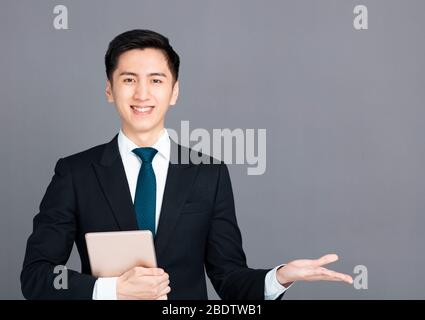 Businessman holding tablet and presenting something in  hand Stock Photo