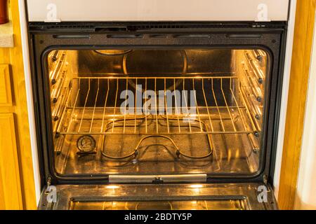 Inside of a convection electric oven showing energized heating coils, oven lights, and cooking shelf. Stock Photo