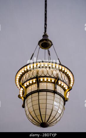 A beautiful antique pendant lamp hangs from a ceiling in a commercial building Stock Photo