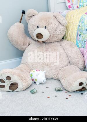 Giant teddy bear holds a hammer and prepares to break a bank to get out more money Stock Photo