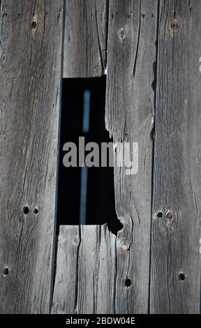 Dark Black Rectangular Shaped Opening of Window in Old Weathered Barn Board Rural Barn With vertical Slats of Grey Weathered Barn Board and Wood Knots Stock Photo