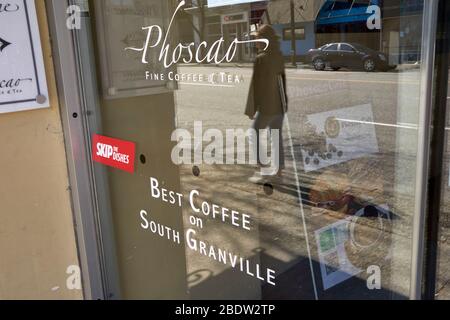 Vancouver, Canada, 09 April 2020. A woman walks by a closed coffee shop during the COVD-19 pandemic. Stock Photo