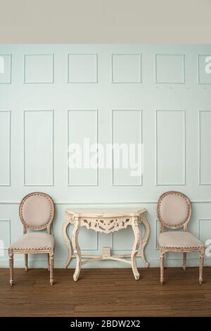 Vintage seat and classical carved wooden table on green background,elegant room with a patterned wall Stock Photo