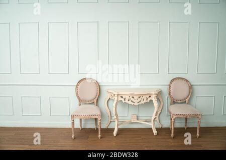 Vintage seat and classical carved wooden table on green background,elegant room with a patterned wall Stock Photo