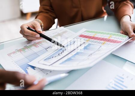 Cropped Image Of Businesswoman Writing On Graph At Desk In Office Stock Photo