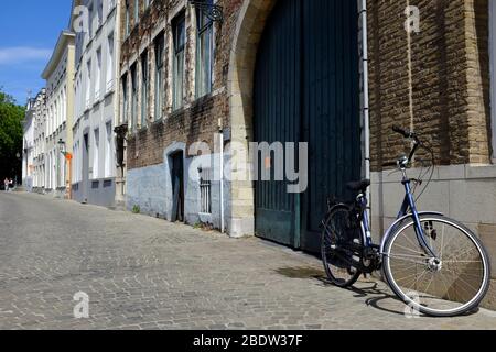 A bicycle parking on cobblestone street outside a historical building in the historical center of Bruges. West Flanders.Belgium Stock Photo