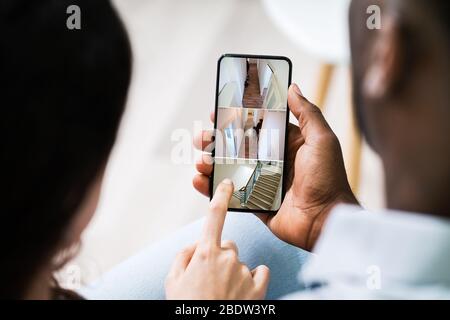 Close Up Of A Person's Hand Using Home Security System On Mobile Phone Stock Photo