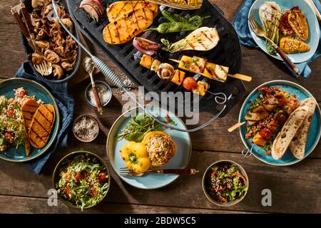 A vegetarian barbecue grill and various gourmet dishes on a rustic timber table. Stock Photo