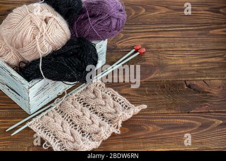 Handmade. Metal knitting needles and woolen threads on a wooden background. Knitting sweaters at home. Hobby. Copy space. Stock Photo