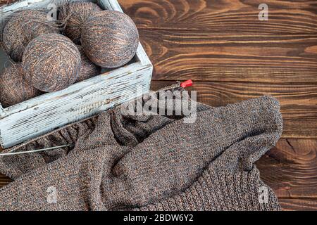 Handmade. Metal knitting needles and woolen threads on a wooden background. Knitting sweaters at home. Hobby. Copy space. Stock Photo