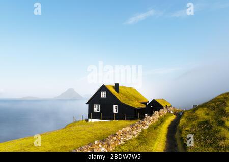 Foggy morning view of a house with typical turf-top grass roof in the Velbastadur village on Streymoy island, Faroe islands, Denmark. Landscape photography