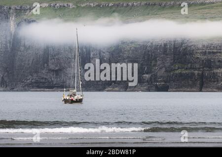 Lonely yacht near Tjornuvik coast on Streymoy Island, Faroe Islands. Landscape photography Stock Photo