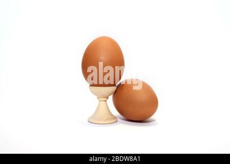 Two brown chicken eggs isolated on the white background. One is in holder. Stock Photo