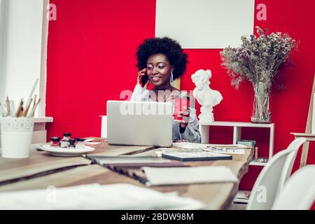 Positive delighted dark-skinned female talking per telephone Stock Photo