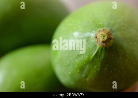 Organic Young Green Mangoes Branch Macro isolated on Wooden Table sour fruits. Stock Photo