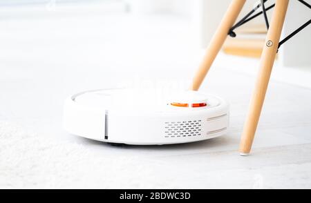 White robotic vacuum cleaner on a floor Stock Photo