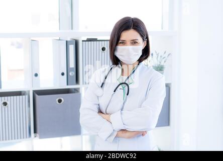 Nice doctor wearing face mask in light office Stock Photo
