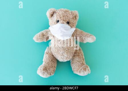 Plush teddy in medical face mask on blue background Stock Photo