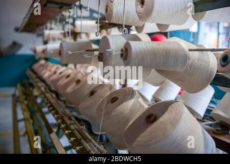 A row of bobbins on a cotton spinning machine Stock Photo